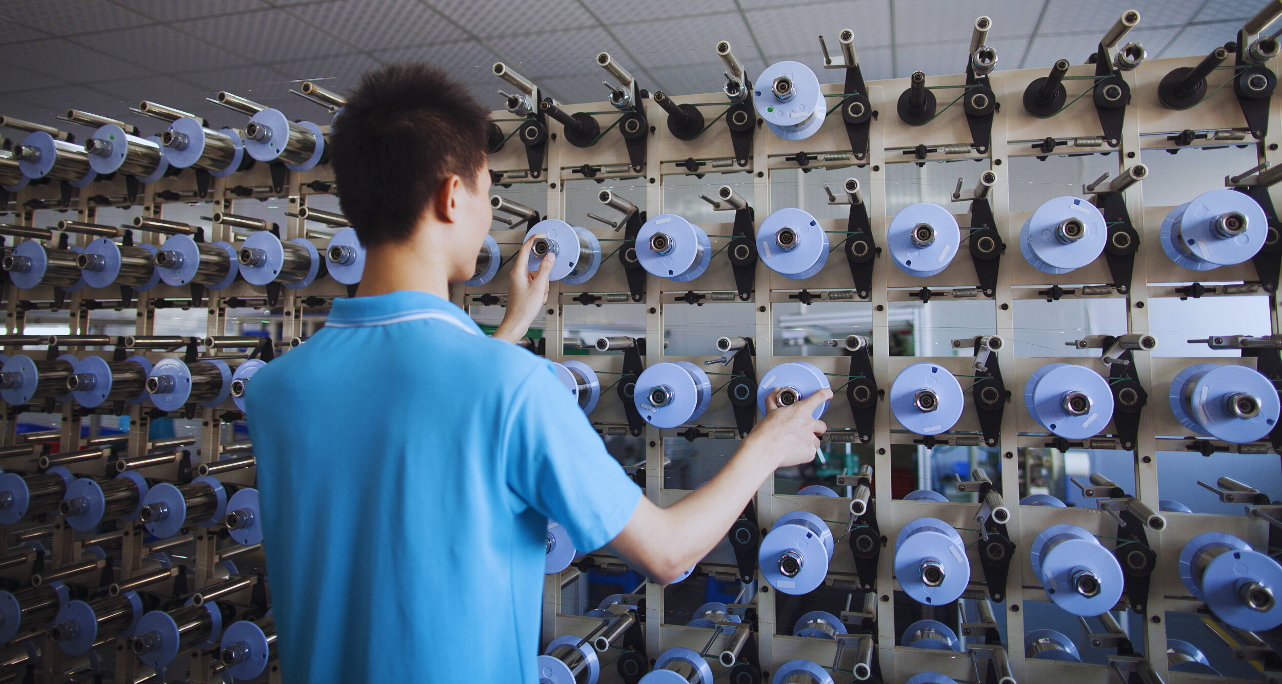 Opérateur surveillant des bobines de fils dans une usine textile en Chine