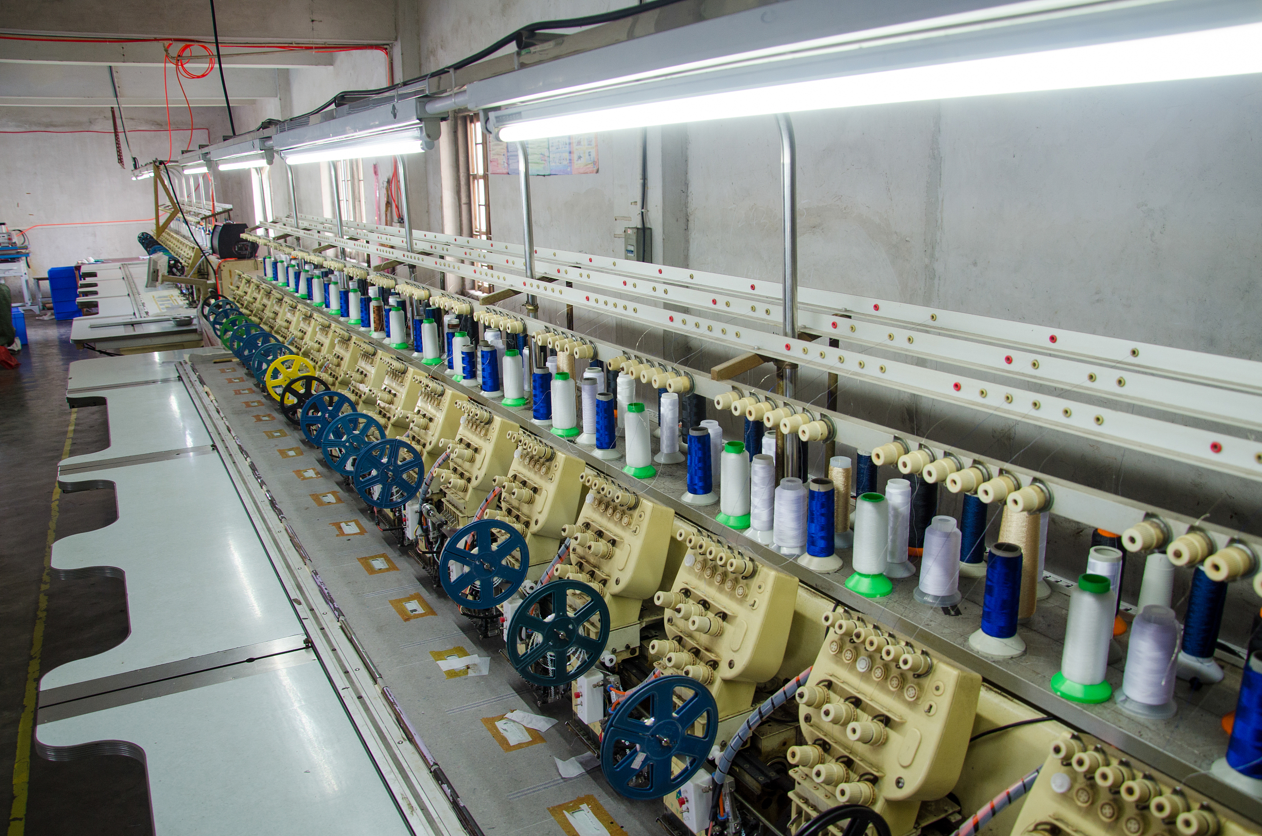 Machines à broder automatiques avec des bobines de fil coloré dans une usine en Chine" Titre : "Technologie de Broderie Avancée"