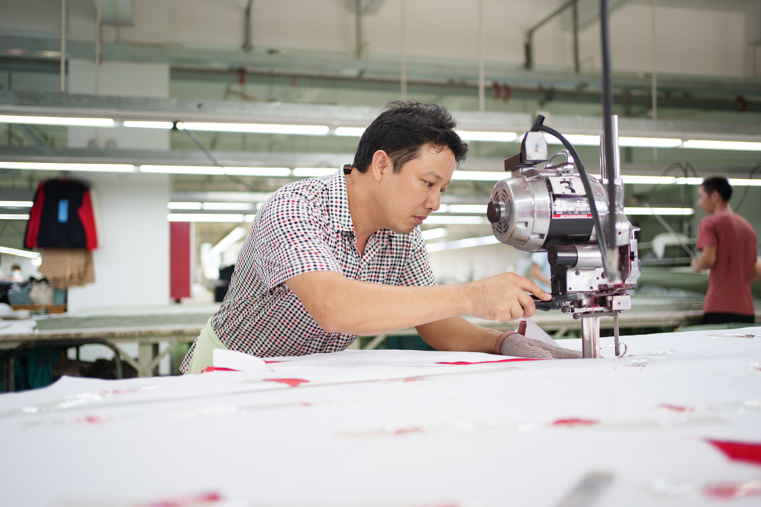 Technicien ajustant une machine à découper le tissu dans un atelier de production